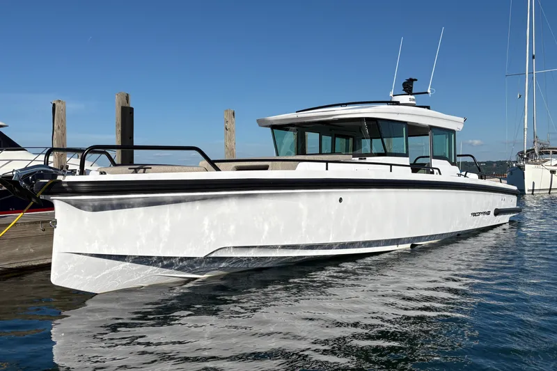 Slide: The Image of 2026 Axopar 37 XC Cross Cabin boat docked on calm water under clear blue sky. - 6