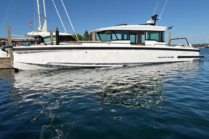 The Image of 2026 Axopar 37 XC Cross Cabin boat docked on calm water under clear blue sky. - 0