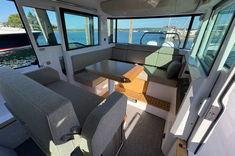 Slide: The Image of 2026 Axopar 37 XC Cross Cabin interior with modern seating and table, overlooking marina. - 47