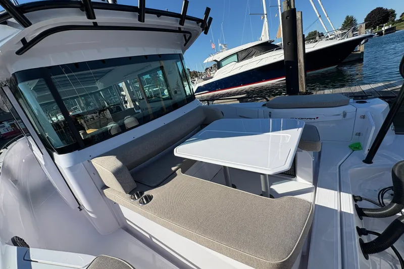 Slide: The Image of 2026 Axopar 37 XC Cross Cabin with outdoor seating and table, docked at marina. - 21