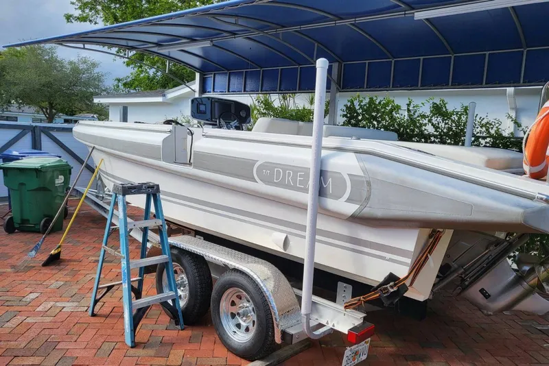 Slide: The Image of 2013 NOVURANIA Chase 23 boat on trailer under canopy, with ladder and cleaning tools nearby. - 3