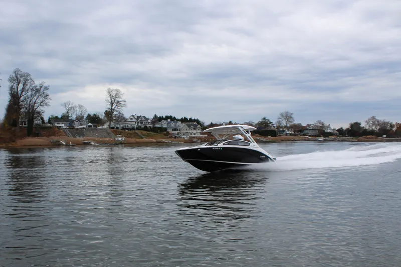 Slide: The Image of 2024 Yamaha 275 SD boat cruising on a calm lake near a residential shoreline. - 11