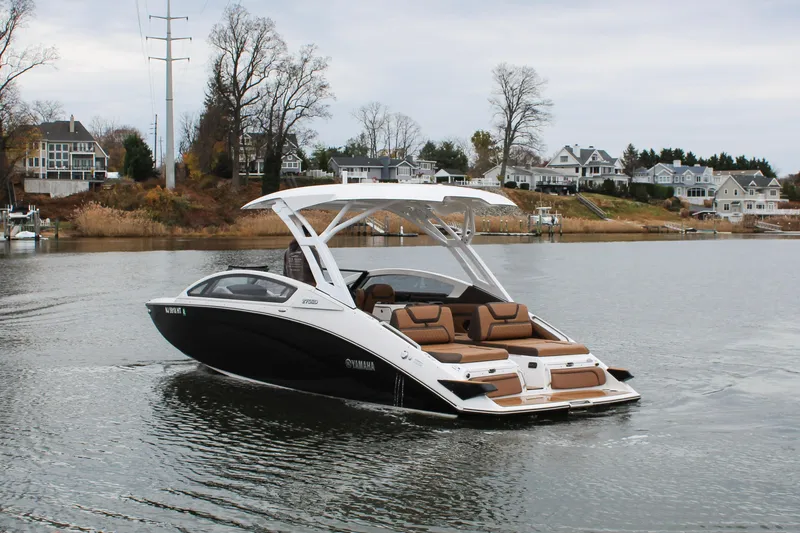 Slide: The Image of 2024 Yamaha 275 SD boat cruising on a serene lake near waterfront homes. - 2