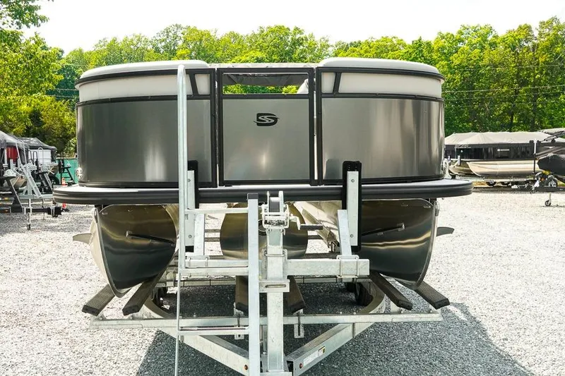 Slide: The Image of 2026 Dockside Pontoons 22DQ on trailer, parked outdoors, surrounded by trees and other boats. - 8