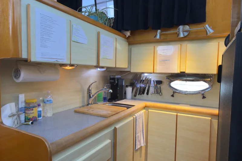 Slide: The Image of Compact kitchen in a 1993 Novatec 44 boat, featuring wooden cabinets and stainless steel fixtures. - 12