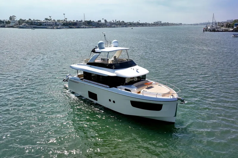 Slide: The Image of 2018 Absolute Navetta 52 yacht cruising on calm waters near a coastal city. - 1