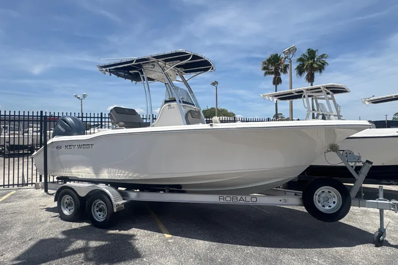 Slide: The Image of 2024 Key West 219 FS boat on trailer, parked outdoors under clear sky. - 7
