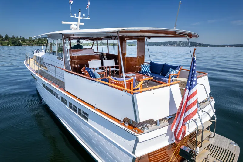 Slide: The Image of 1965 Chris-Craft 57 Constellation yacht on calm water, featuring elegant deck seating and American flag. - 10