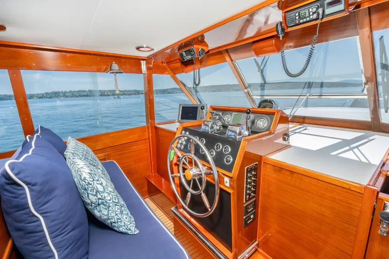 Slide: The Image of 1965 Chris-Craft 57 Constellation yacht interior with wooden helm and blue cushioned seating. - 13