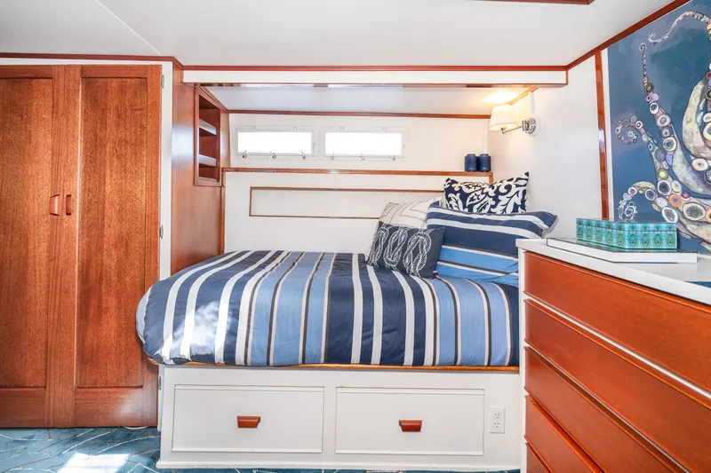 Slide: The Image of 1965 Chris-Craft 57 Constellation bedroom with striped bedding and wooden cabinetry. - 37