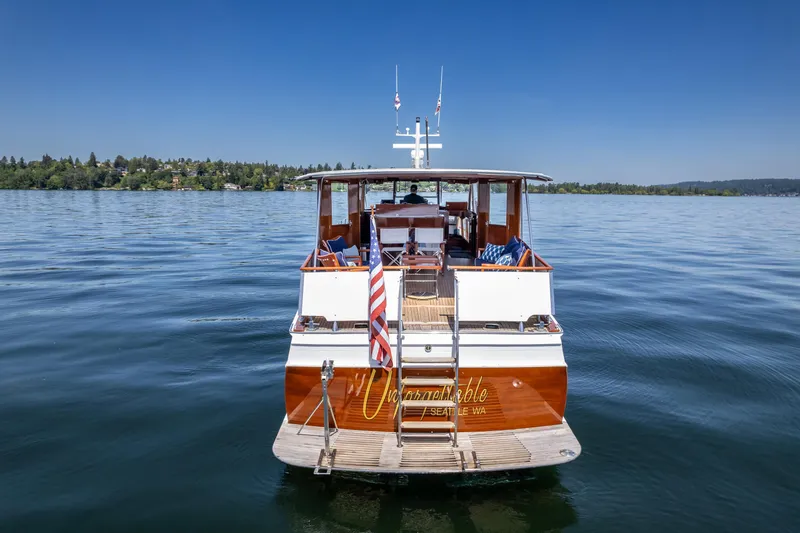 Slide: The Image of 1965 Chris-Craft 57 Constellation yacht on calm water, rear view with American flag. - 8