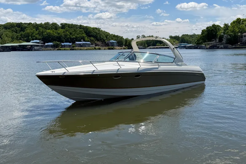 The Image of 2003 Formula 330 Sun Sport boat on a serene lake under a partly cloudy sky. - 1