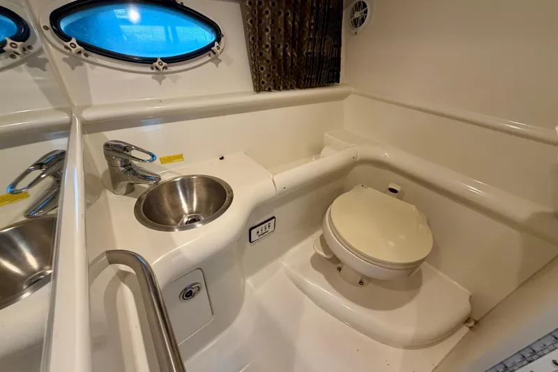 Slide: The Image of 2003 Formula 330 Sun Sport boat bathroom with sink, toilet, and porthole window. - 38