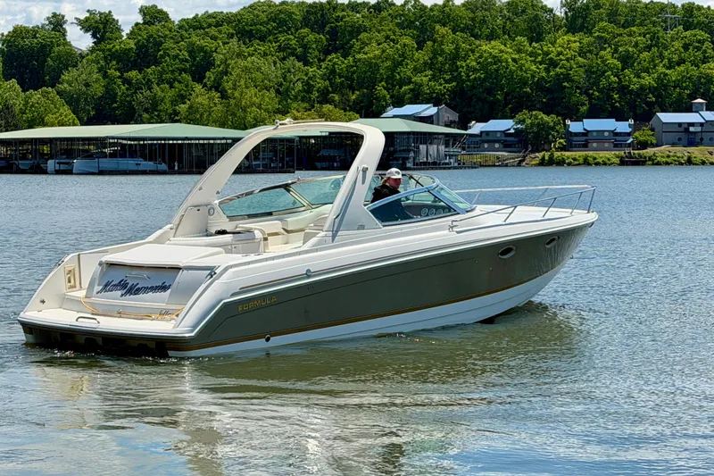 Slide: The Image of 2003 Formula 330 Sun Sport boat cruising on a scenic lake with lush greenery. - 6