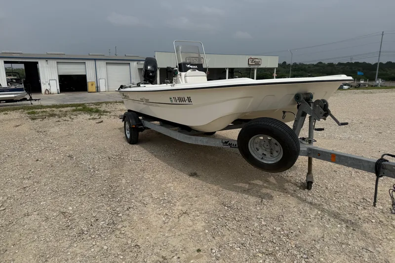 Slide: The Image of 2015 Mako Pro Skiff 17 CC boat on trailer, parked outdoors near a garage. - 4