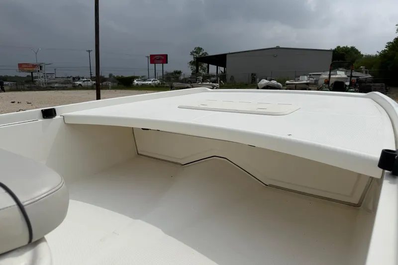 Slide: The Image of 2015 Mako Pro Skiff 17 CC boat interior with storage compartment, overcast sky background. - 8