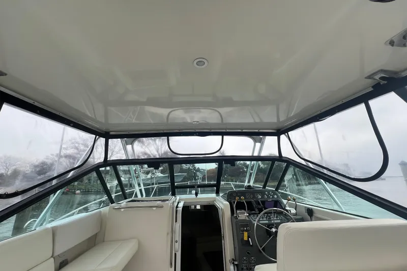 Slide: The Image of 1993 Tiara Yachts 3100 Open cockpit with steering wheel and seating, docked by the water. - 15