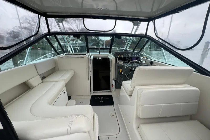 Slide: The Image of 1993 Tiara Yachts 3100 Open interior with white seating and helm, docked by the water. - 2