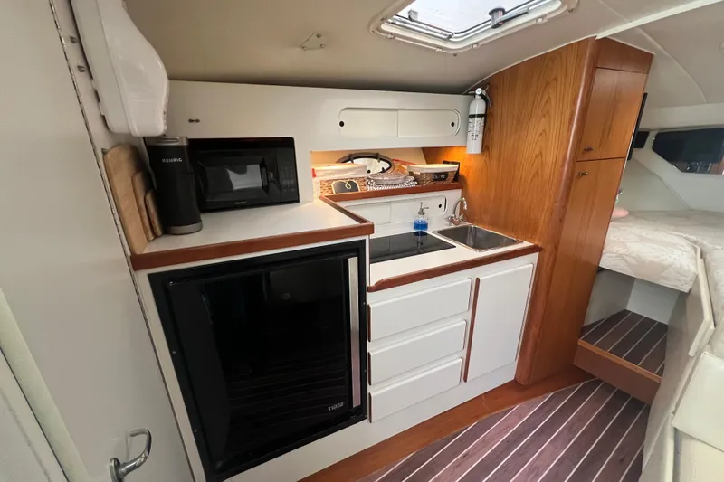 Slide: The Image of 1993 Tiara Yachts 3100 Open interior with kitchenette, featuring sink, microwave, and storage. - 22