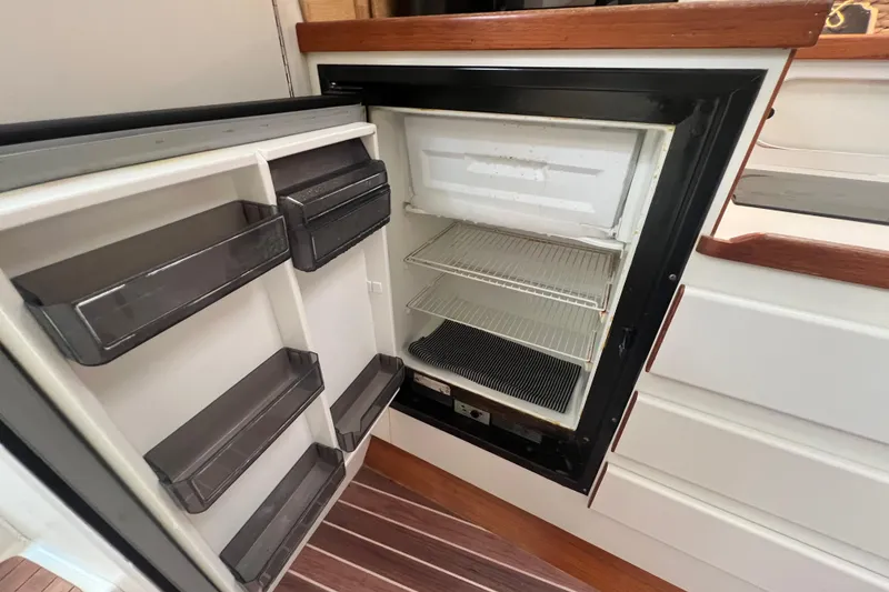 Slide: The Image of Open refrigerator inside 1993 Tiara Yachts 3100 Open, showcasing interior shelves and storage. - 23