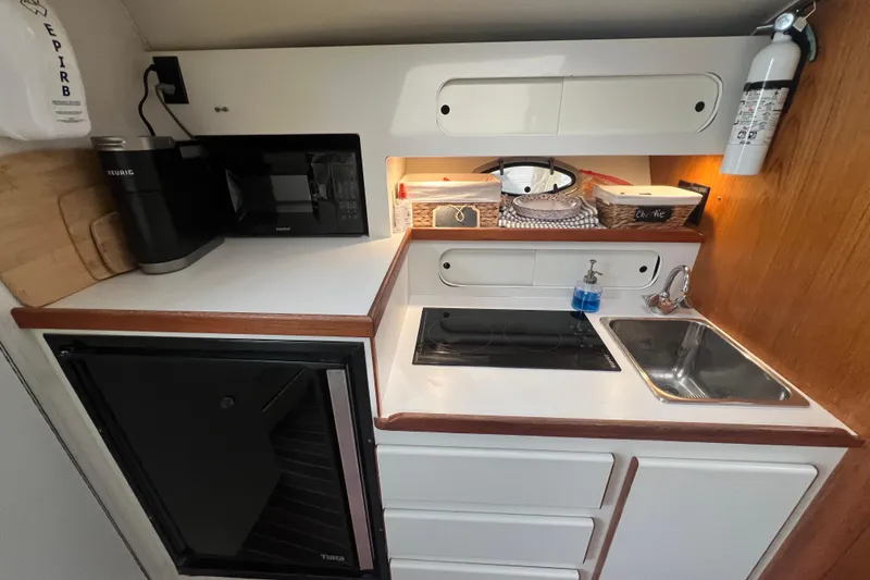 Slide: The Image of Compact kitchen in a 1993 Tiara Yachts 3100 Open, featuring appliances and storage. - 3