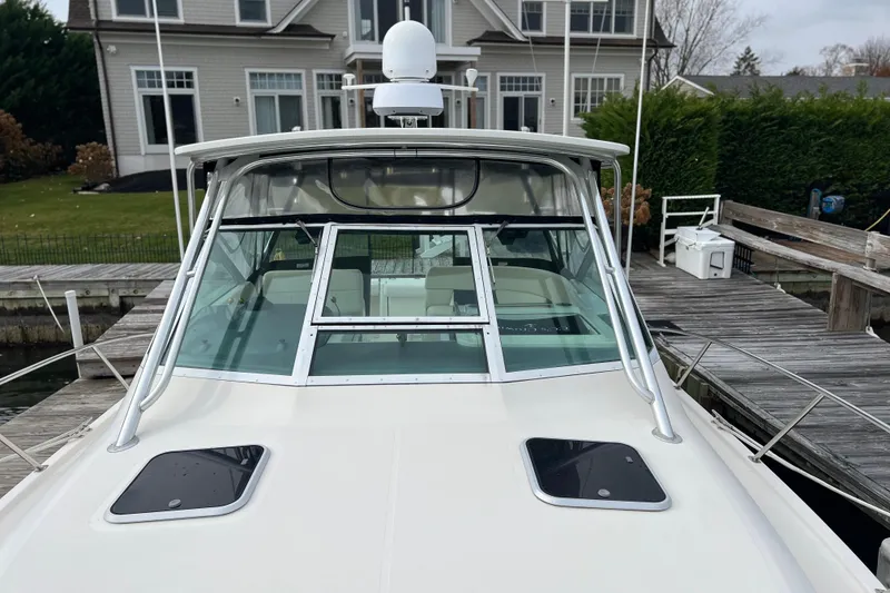 Slide: The Image of 1993 Tiara Yachts 3100 Open docked near a house, showcasing its sleek design. - 31