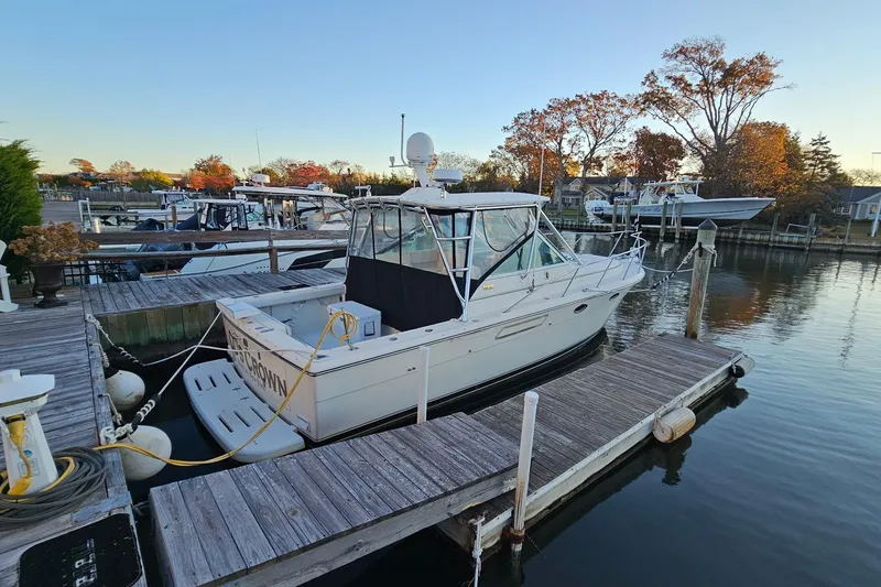 Slide: The Image of 1993 Tiara Yachts 3100 Open docked at a serene marina with autumn trees. - 36