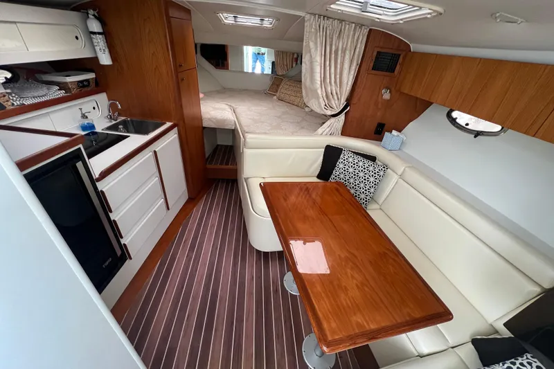 Slide: The Image of 1993 Tiara Yachts 3100 Open interior with kitchenette, dining area, and cozy sleeping quarters. - 4