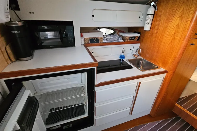 Slide: The Image of Compact kitchen area in a 1993 Tiara Yachts 3100 Open, featuring a sink, microwave, and fridge. - 40