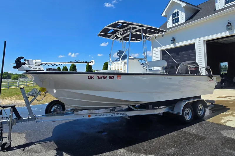 Slide: The Image of 2017 Boston Whaler 210 Montauk boat on trailer, parked near a garage under clear blue sky. - 35