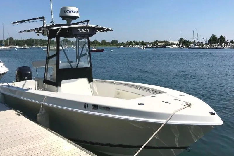 The Image of 1999 Contender 23 Open boat docked by the water on a sunny day. - 0