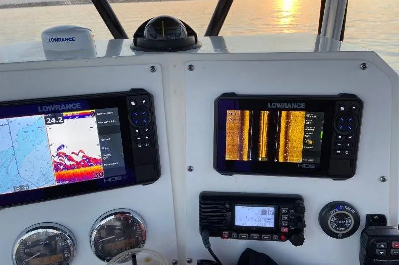 Slide: The Image of 1999 Contender 23 Open boat dashboard with Lowrance navigation displays at sunset. - 17