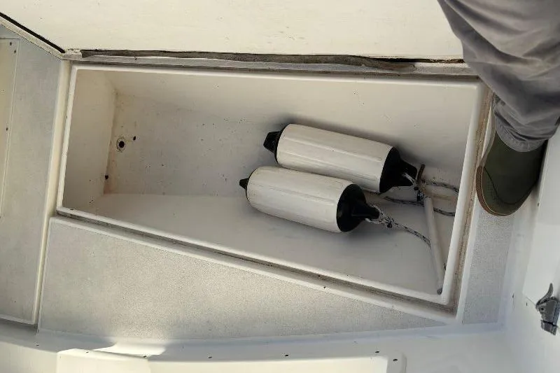 Slide: The Image of Open storage compartment on 1999 Contender 23 Open boat with two white fenders inside. - 18