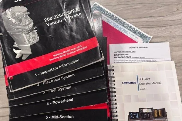 Slide: The Image of Manuals and documents for a 1999 Contender 23 Open boat, including engine and GPS guides. - 27