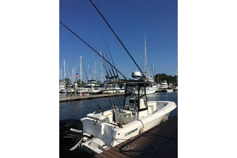 Slide: The Image of 1999 Contender 23 Open fishing boat docked at marina with fishing rods. - 3