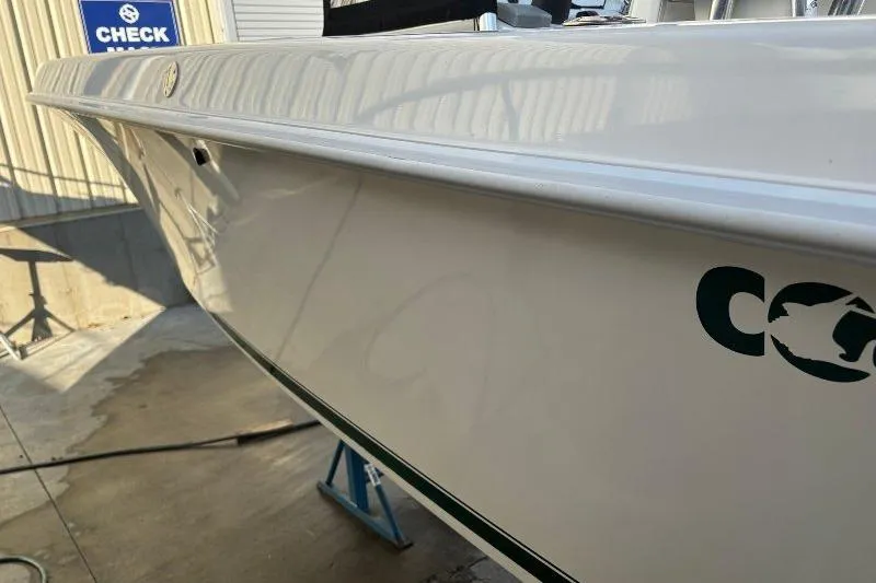 Slide: The Image of 1999 Contender 23 Open boat side view, white hull with logo, in a maintenance area. - 7