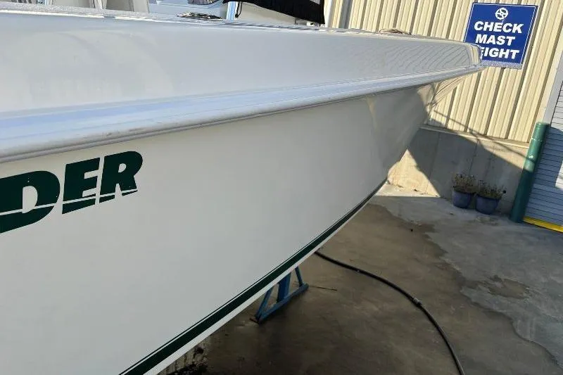 Slide: The Image of 1999 Contender 23 Open boat side view, white hull with green lettering, docked outdoors. - 8