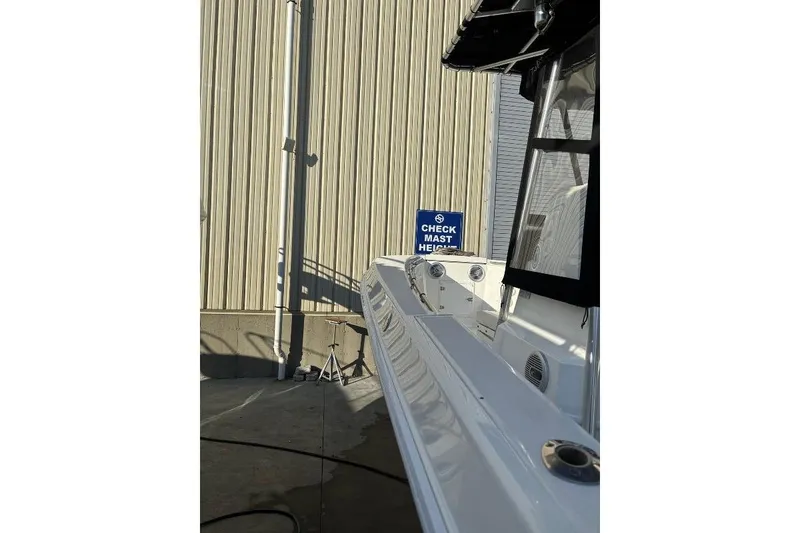 Slide: The Image of 1999 Contender 23 Open boat near a "Check Mast Height" sign, docked beside a building. - 9