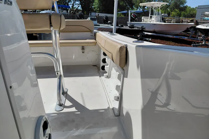 Slide: The Image of 2020 NauticStar 20 XS boat interior with seating and rod holders, docked outdoors. - 21