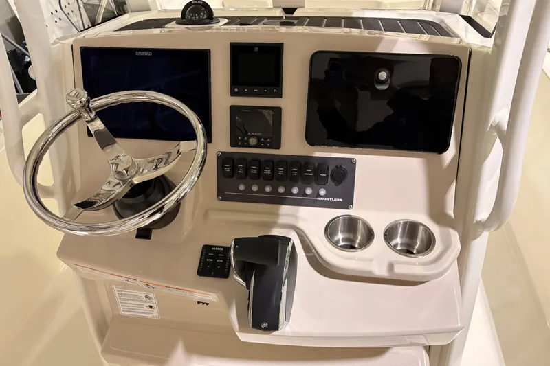 Slide: The Image of 2026 Boston Whaler 250 Dauntless helm with steering wheel, controls, and cup holders. - 12