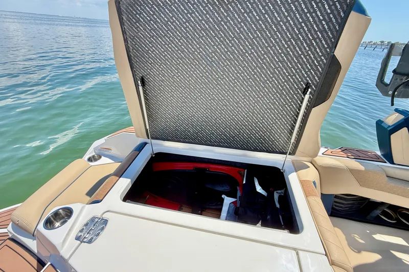 Slide: The Image of Open storage compartment on 2021 Nautique Super Air Nautique G21 boat by the water. - 20