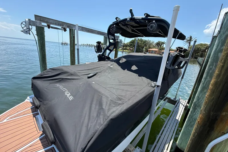 Slide: The Image of 2021 Nautique Super Air Nautique G21 boat covered at dockside, sunny waterfront view. - 31