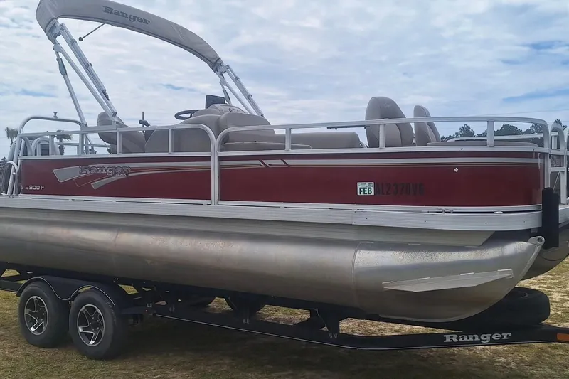The Image of 2021 Ranger Reata 200F pontoon boat on trailer, red and silver design. - 1