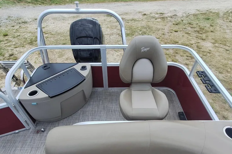 Slide: The Image of 2021 Ranger Reata 200F boat interior with seating and motor, on grassy terrain. - 10