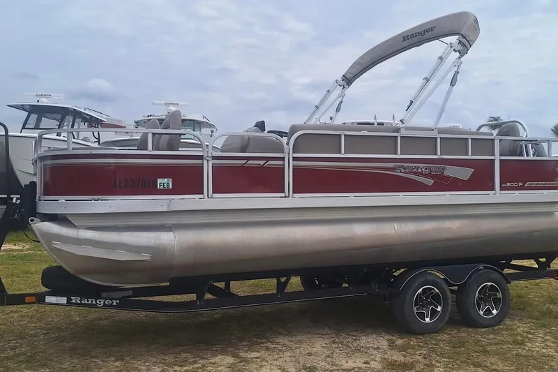 Slide: The Image of 2021 Ranger Reata 200F pontoon boat on trailer, red and silver design. - 6