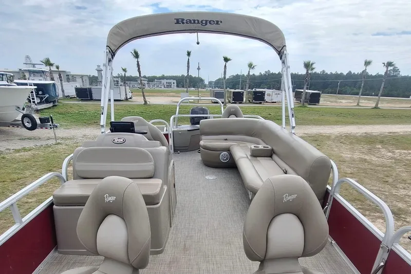 Slide: The Image of 2021 Ranger Reata 200F pontoon boat with beige seating and canopy, parked outdoors. - 7