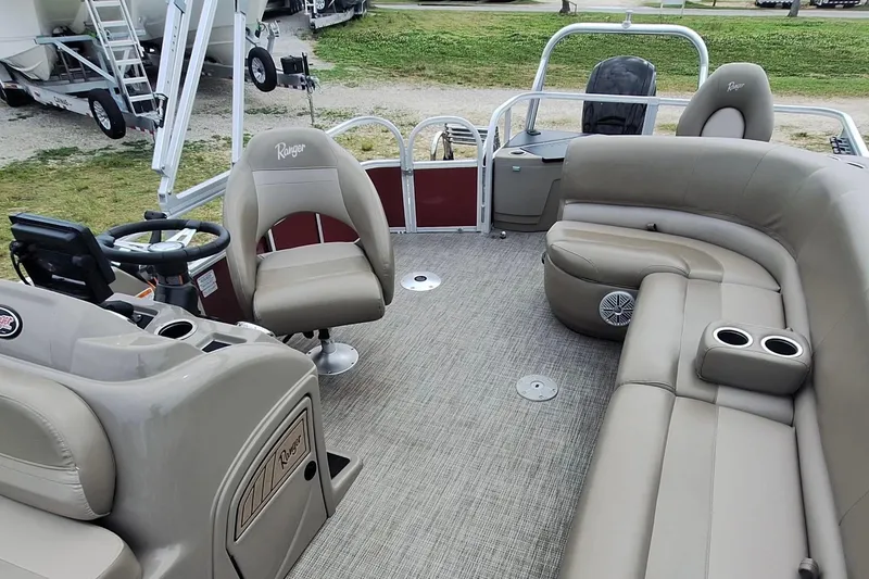 Slide: The Image of 2021 Ranger Reata 200F pontoon boat interior with beige seating and steering console. - 9