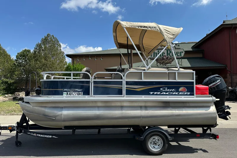 The Image of 2024 Sun Tracker Bass Buggy 16 XL Select pontoon boat on trailer, outdoors. - 0