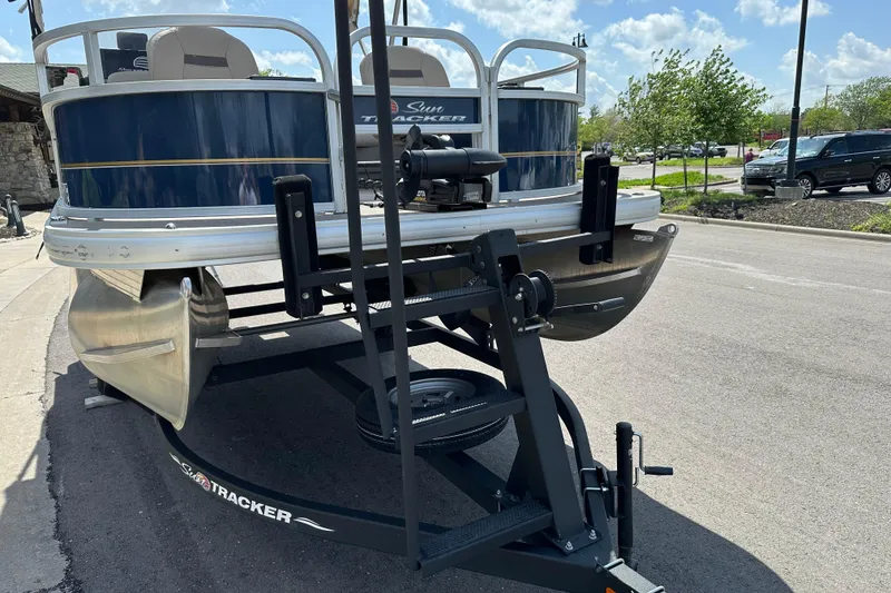 Slide: The Image of 2024 Sun Tracker Bass Buggy 16 XL Select pontoon boat on trailer, parked outdoors. - 11