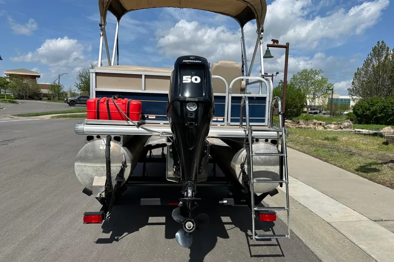Slide: The Image of 2024 Sun Tracker Bass Buggy 16 XL Select pontoon boat with Mercury 50 engine, parked outdoors. - 9